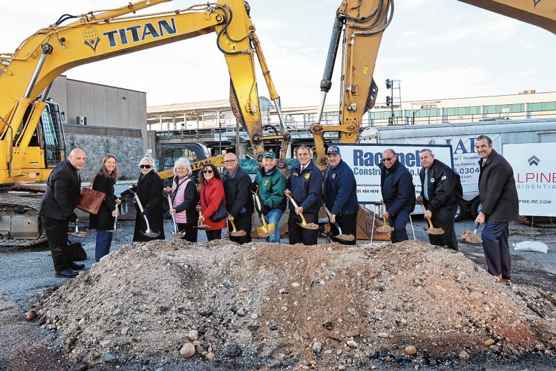 Town officials with shovels, standing behind a large mound of dirt.