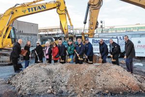 Town officials with shovels, standing behind a large mound of dirt.