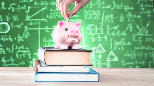 Female putting coin into piggy bank (Getty Images)