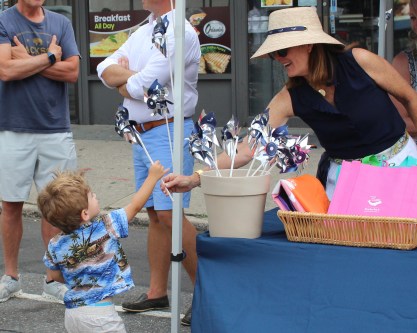A woman at the Daniel Gale Sotheby's International Real Estate booth hands a pinwheel to a boy.