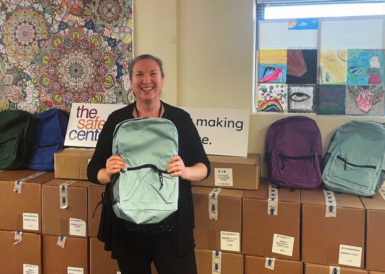 Debbie Lyons, Associate Executive Director of The Safe Center, with boxes full of backpacks. (Photo Credit The Safe Center)